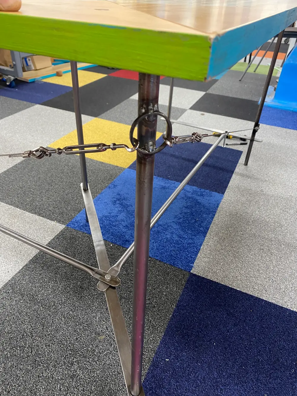 Close-up view of the steel frame and green plywood top of the corner desk prototype.