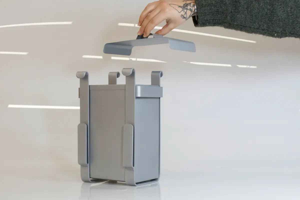 A fabricated metal composting unit, 'Scrappy', is shown with a hand demonstrating the integrated handle.