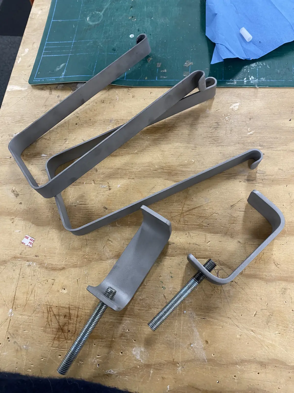Several fabricated metal trough and bracket components laid out on a workbench.