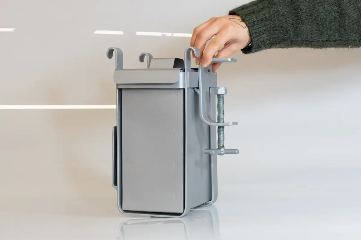 A fabricated metal prototype of the composting unit is shown with a hand interacting with the mechanism.