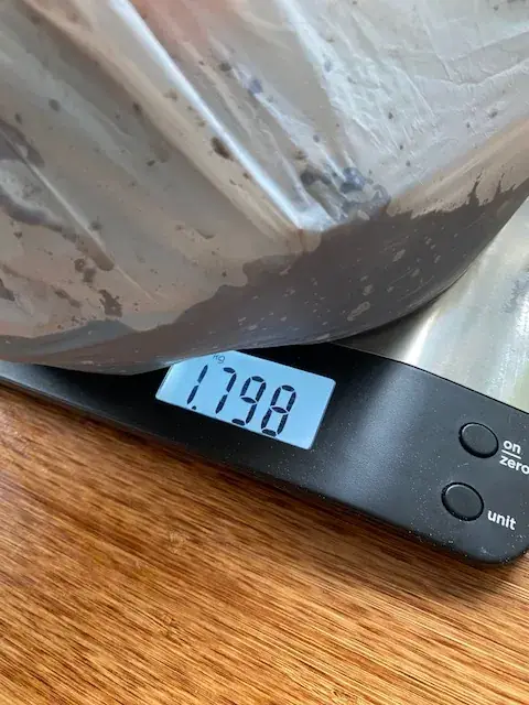 The metal 'Scrappy' composting unit resting on a digital kitchen scale during fabrication.
