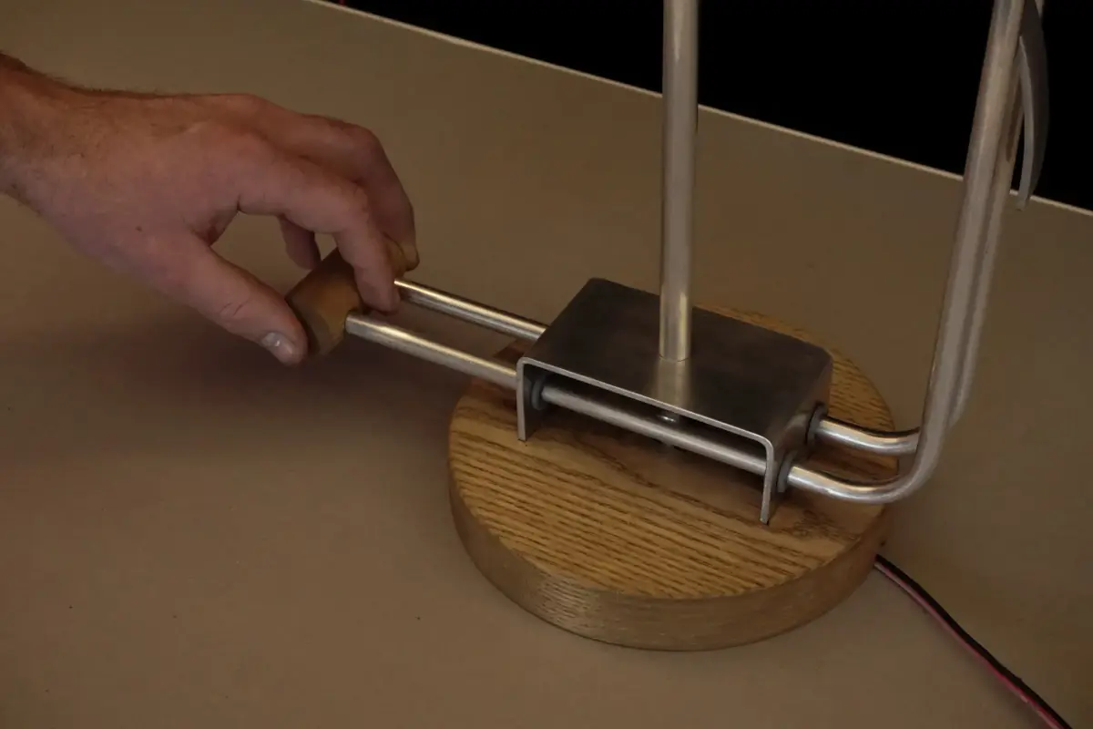 Hand interacting with the metal and wood base of the lamp prototype.
