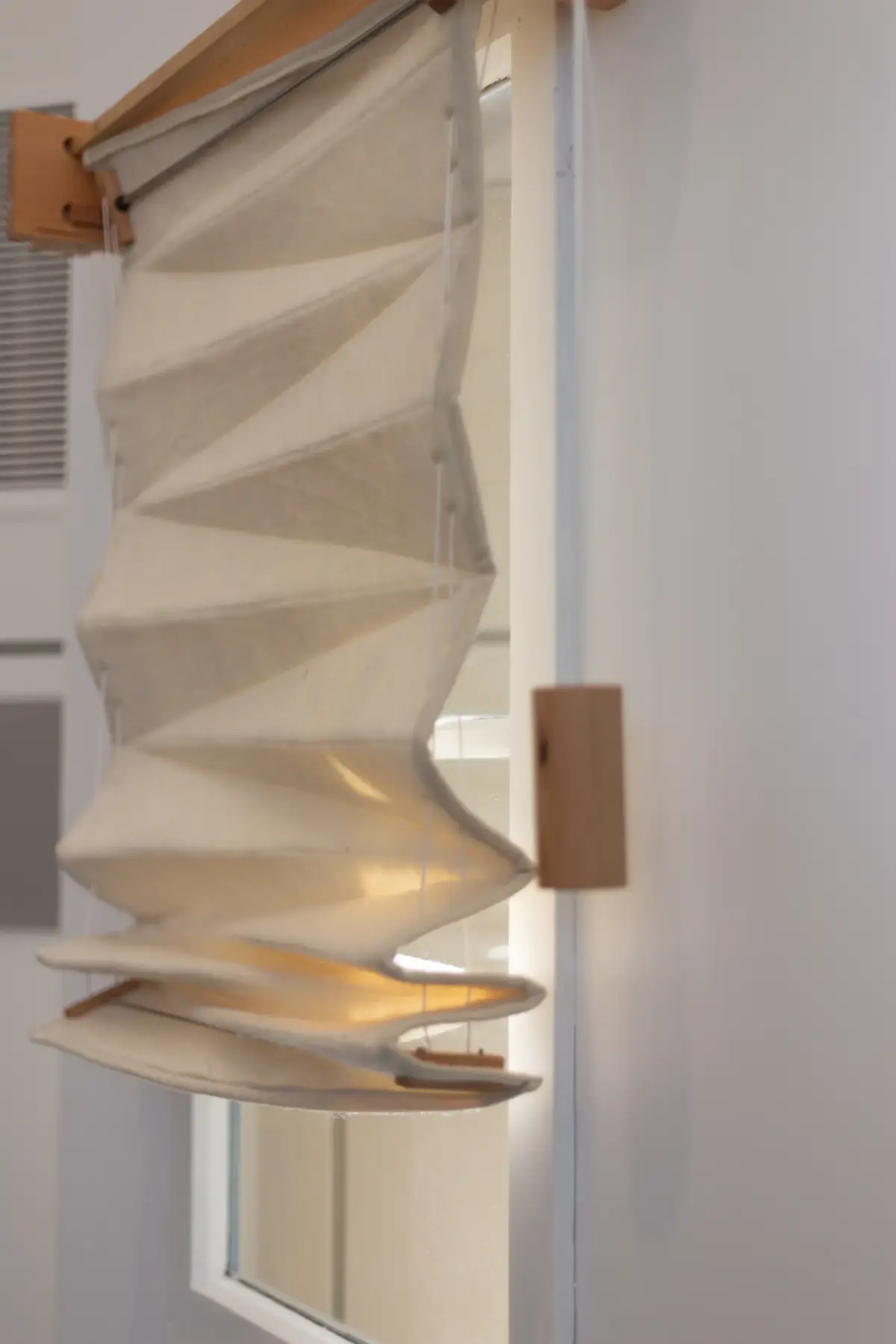 A prototype pendant lamp featuring layered wood and draped textile material.