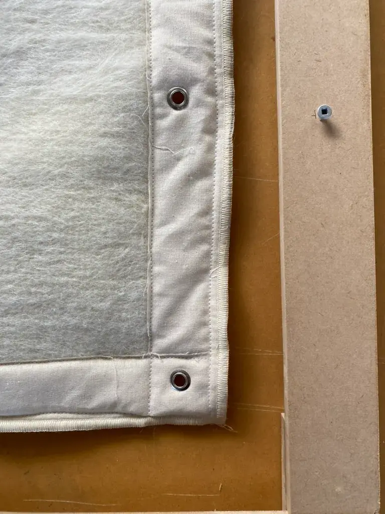 A light-colored textile panel, possibly linen, showing three visible metal grommets for a homeware project.
