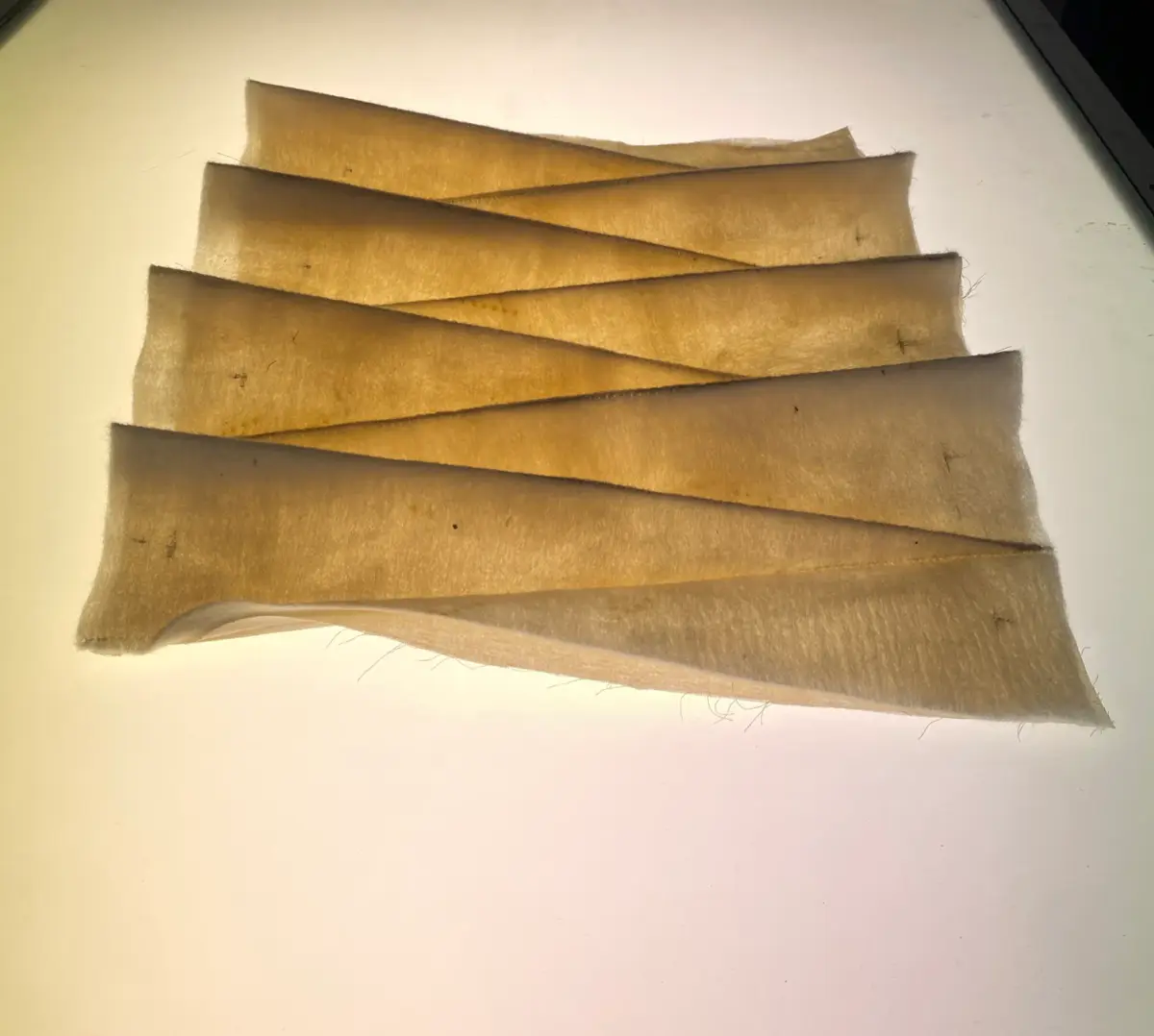 Several natural-toned textile strips are laid out in a diagonal, layered arrangement for the 'Contour' project.