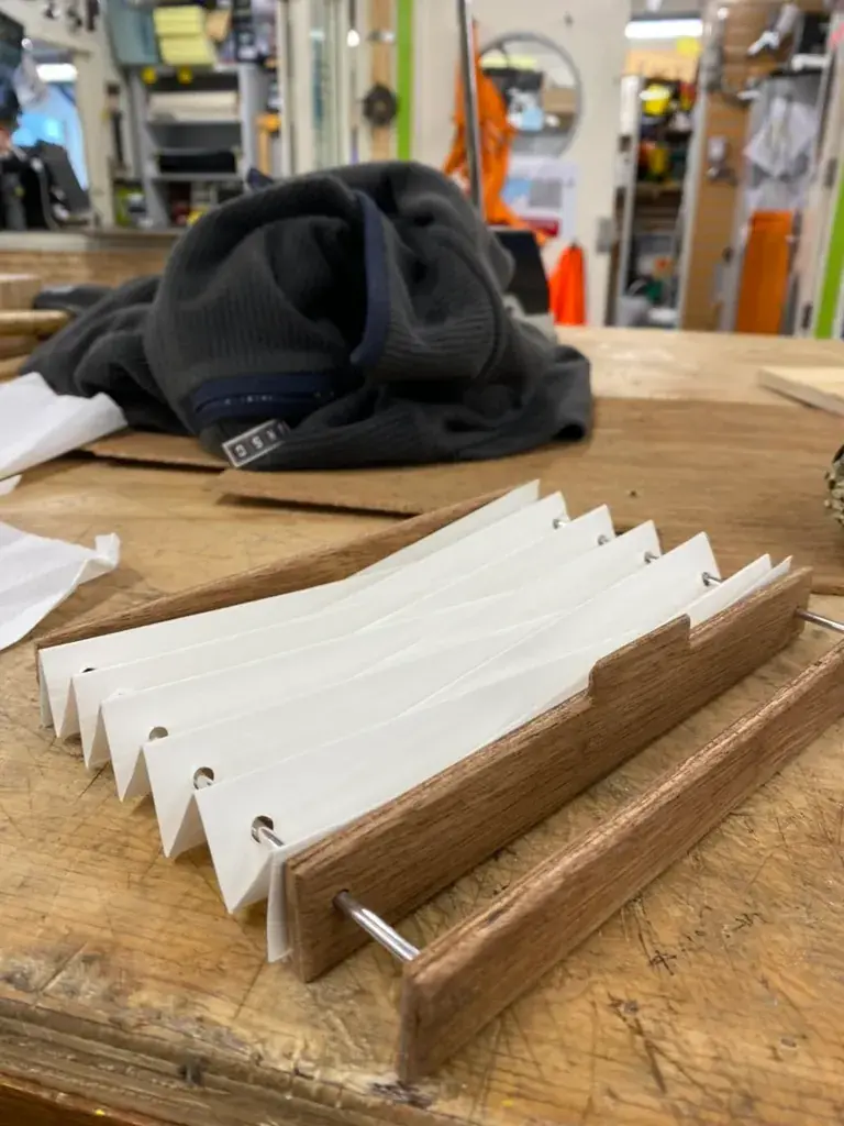 A wooden frame holding several white paper photos, staged on a workbench with textiles.