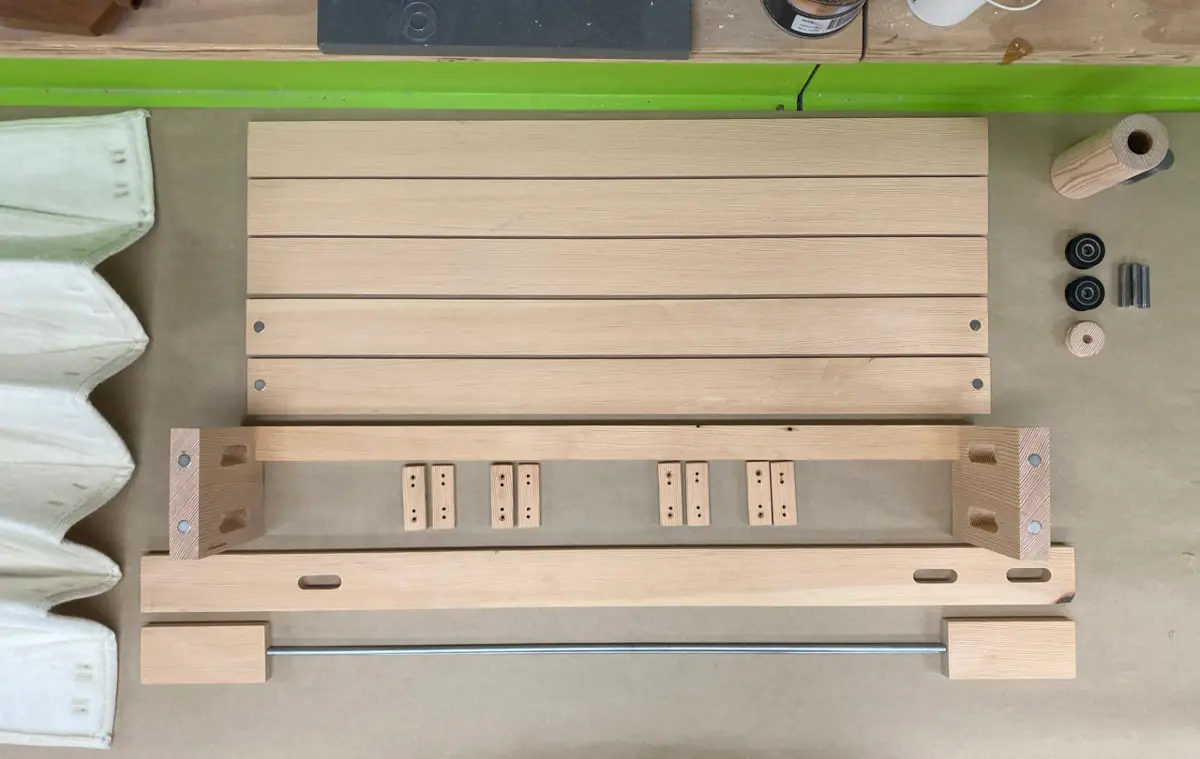 Assortment of raw wooden components, including slats and rails, laid out for fabrication.
