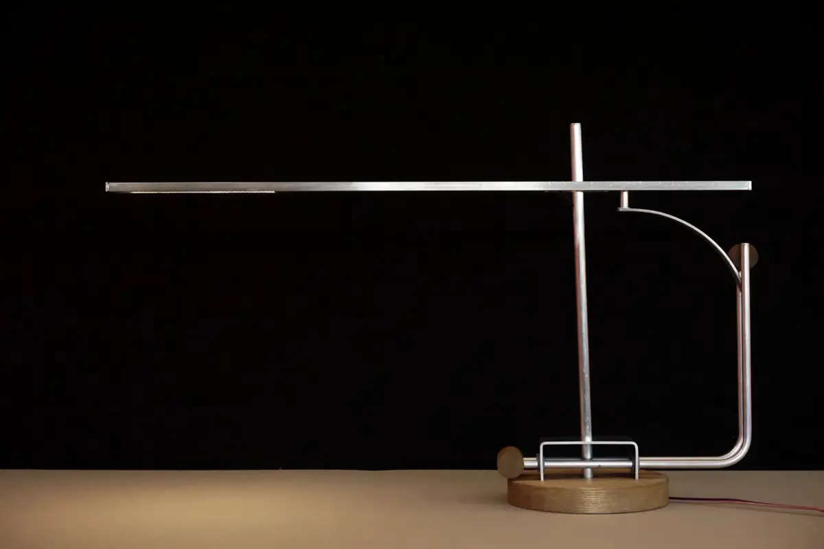 A finished metal and wood lamp, 'Tei', displayed on a surface against a black background.