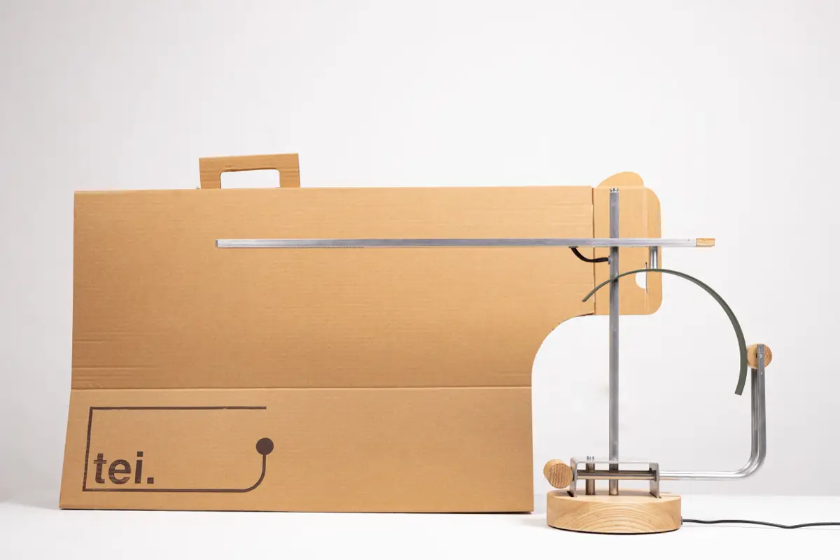 The finished metal and wood lamp is displayed next to its brown cardboard retail packaging.